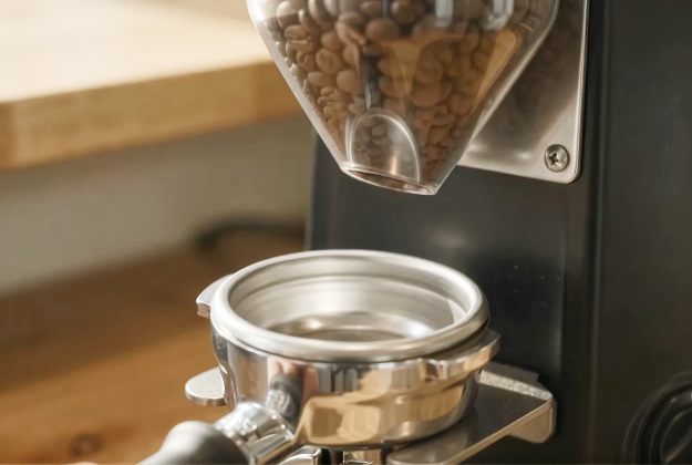 A grinder dosing ground coffee into a portafilter